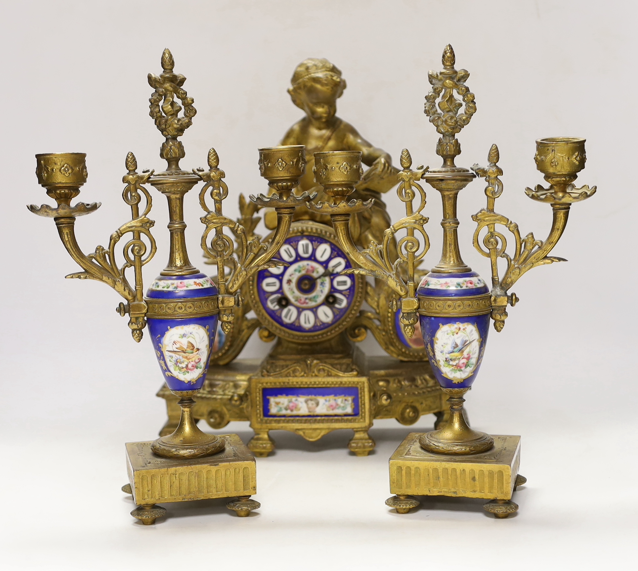 A 19th century ornate French gilt brass and porcelain clock, with two matching two branch candelabra garnitures, clock 31cm high